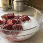 Deer meat soaking in salt water in a glass bowl