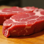 Raw beef ribeye steak on a wooden board.